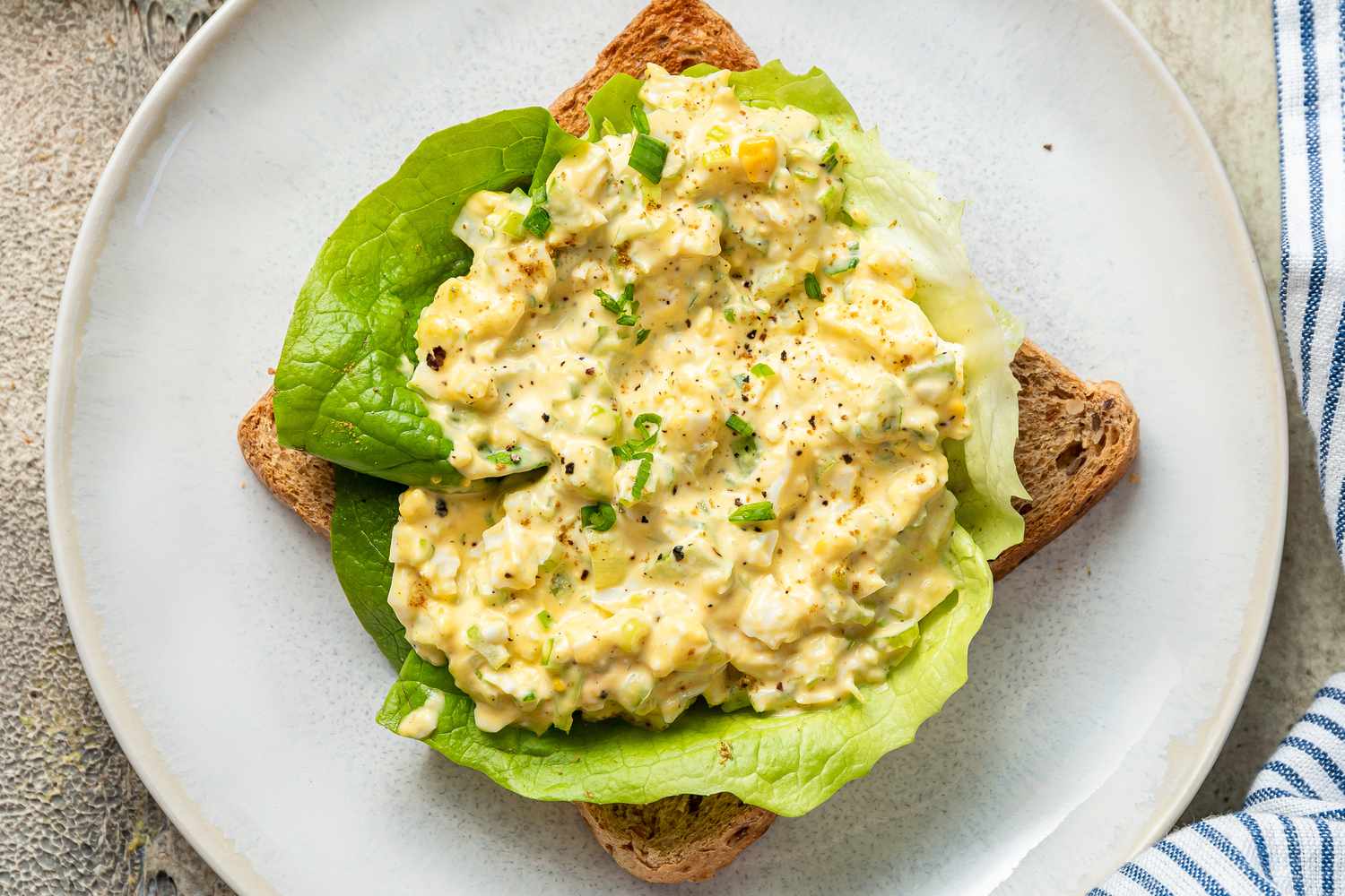 Egg salad on a piece of lettuce-topped toast