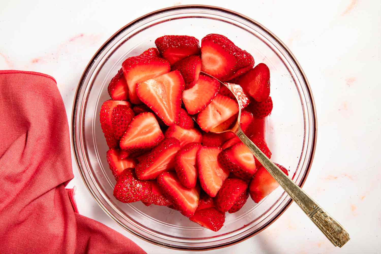 Sliced strawberries in a bowl with a spoon