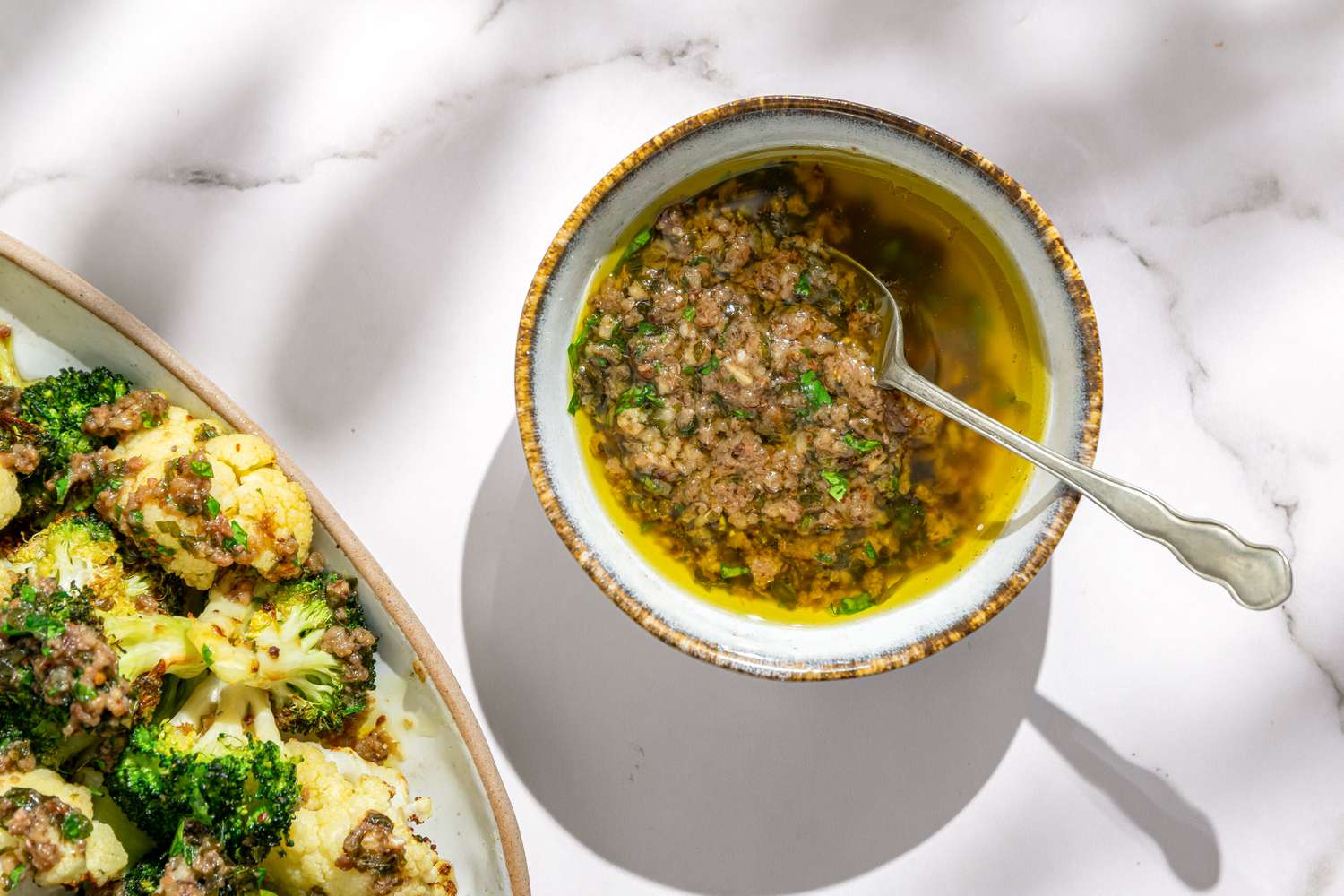 Overhead closeup shot of a bowl with bagna cauda on a white marble counter