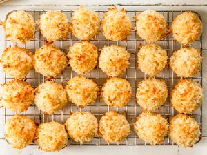 Overhead view of a cooling rack of twenty four macaroon cookies on a wooden table background