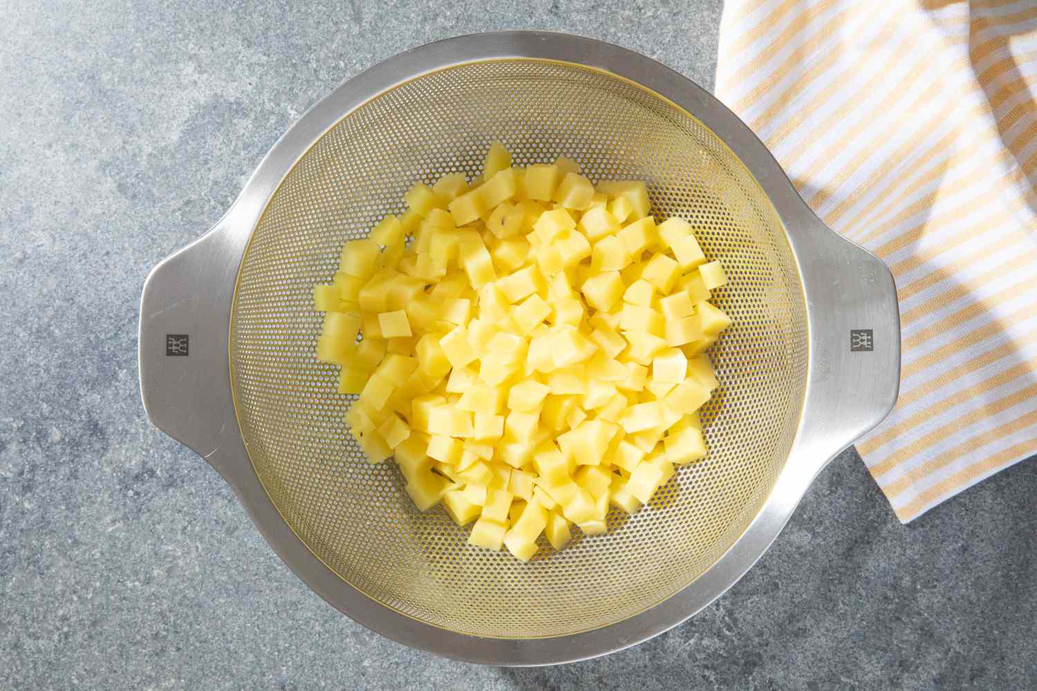 cooked diced potatoes in a colander for olivier potato salad recipe