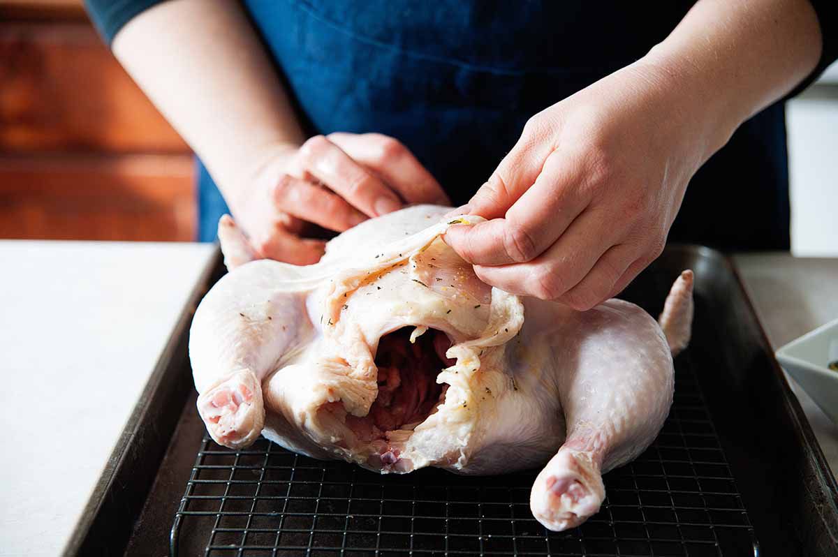How to Roast a Whole Chicken - woman separating chicken skin from meat