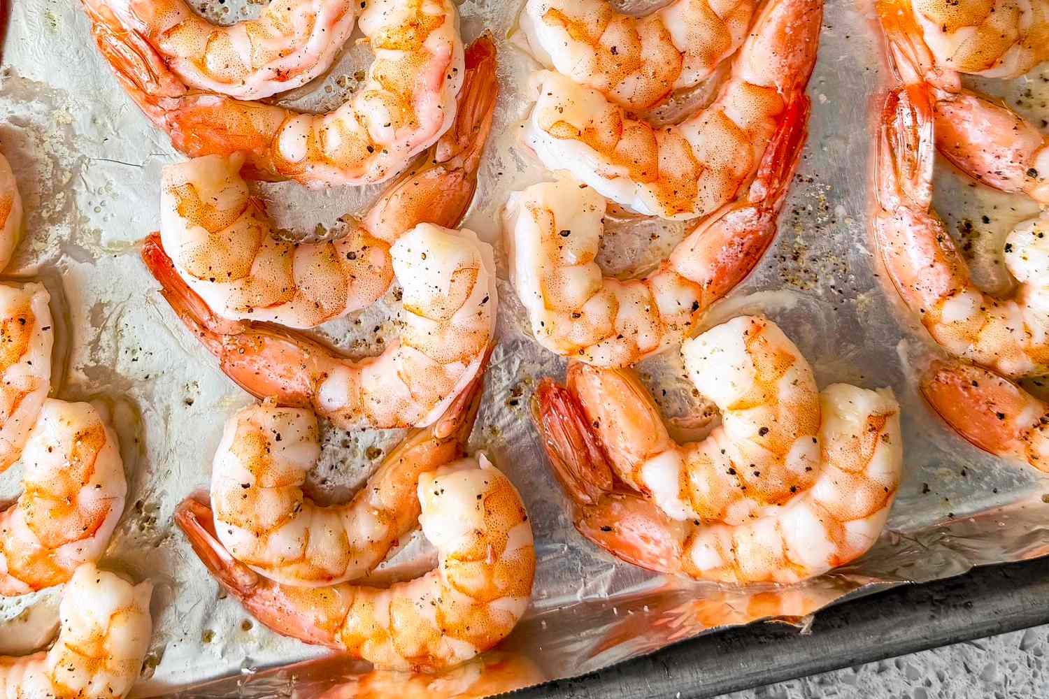 Cooked shrimp laid out on a baking sheet
