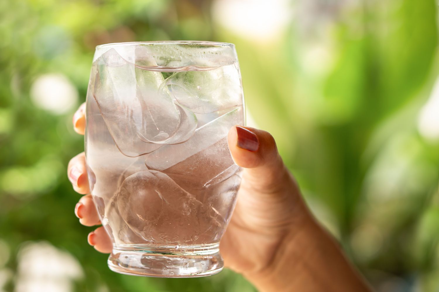A hand holding a glass of iced water