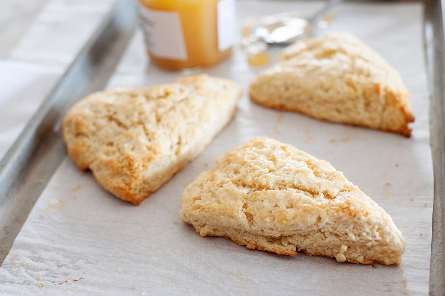 Close up of American-Style Scones on parchment with jam.