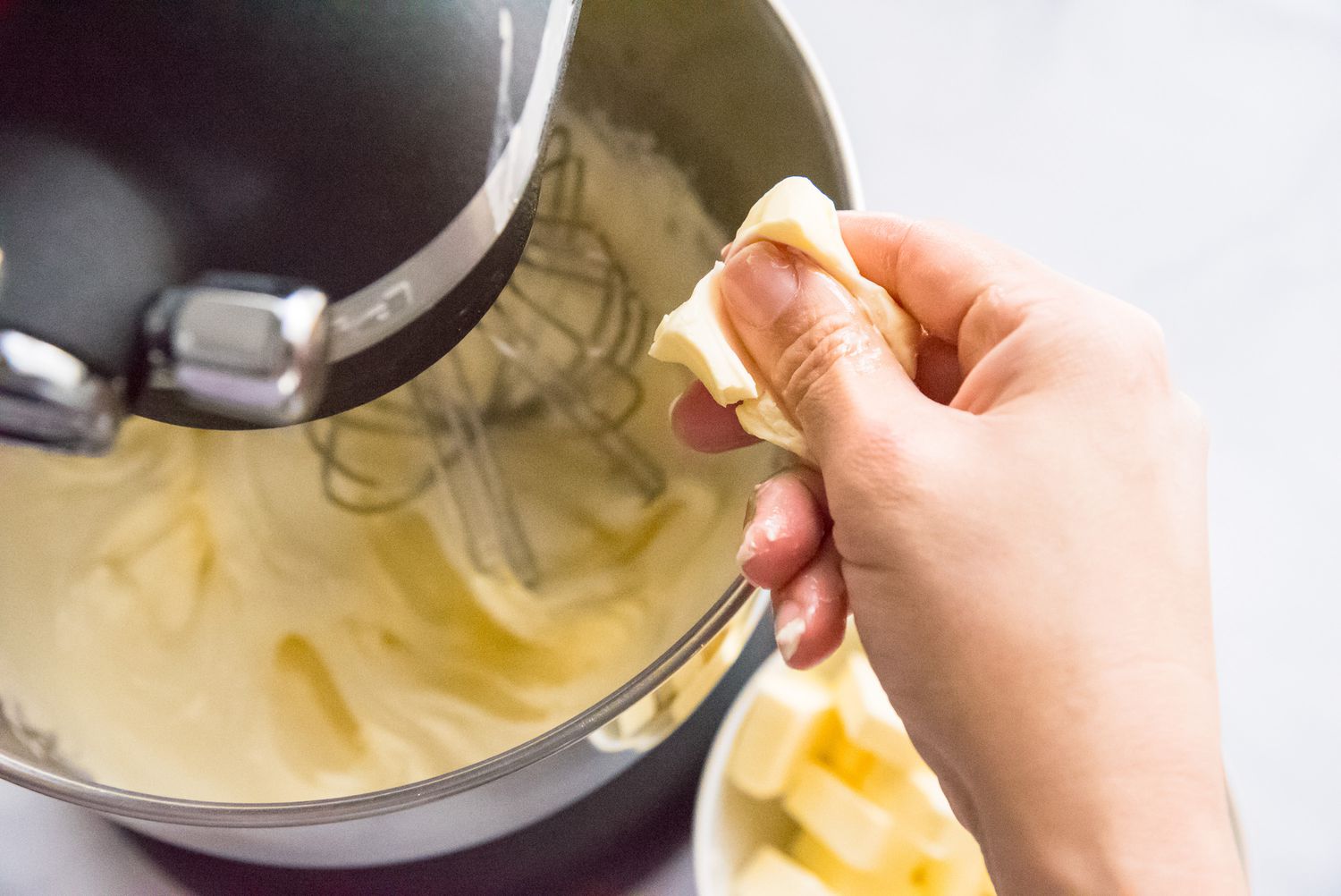Adding butter to mixer to show how to make French buttercream frosting.