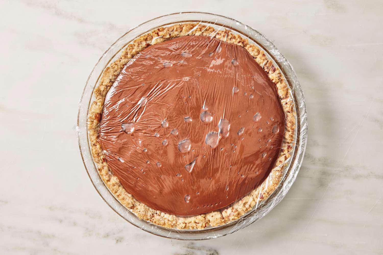 overhead view of pie shell with chocolate filling added, plastic wrap covering the pie for Arkansas Possum Pie recipe