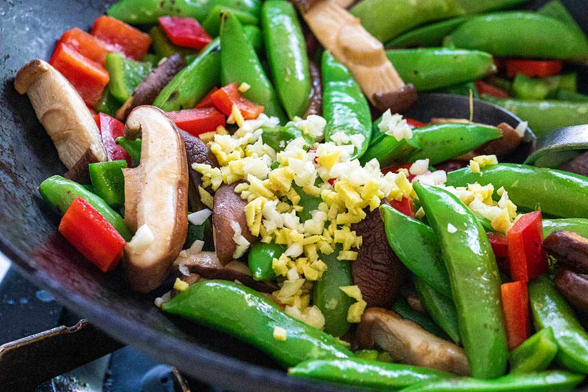 Snap peas, mushrooms, and red peppers in a wok to make an Easy Tofu Stir Fry.