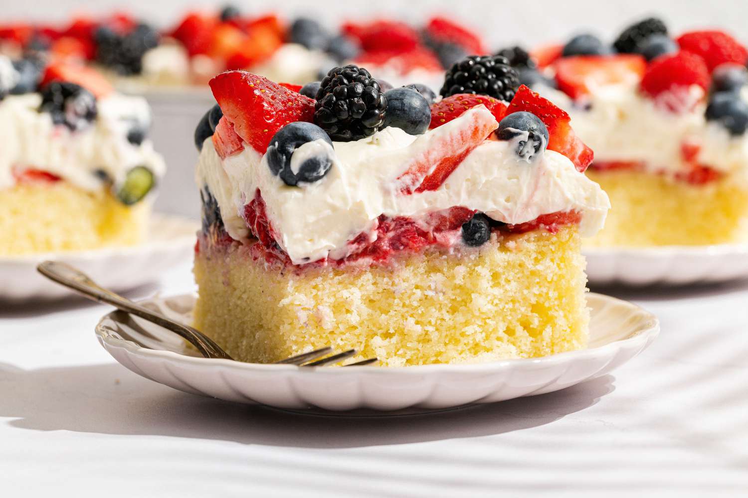 slice of Easy Berry Chantilly Cake on a small plate with a fork