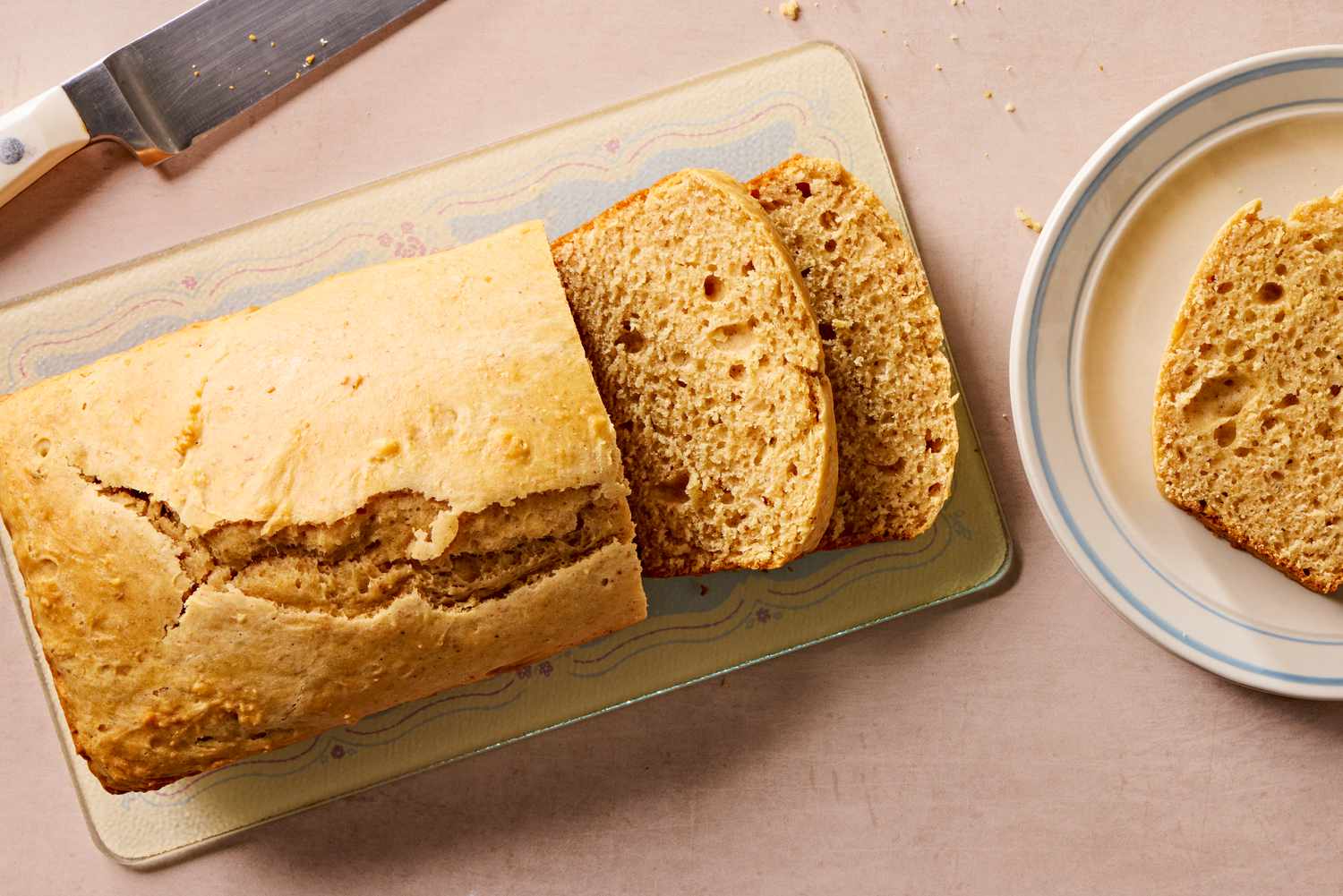 Overhead view of a loaf of retro peanut butter bread next to a plate with a slice