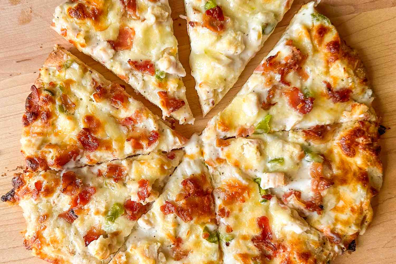 A gooey baked pizza showing bits of bacon and chunks of chicken