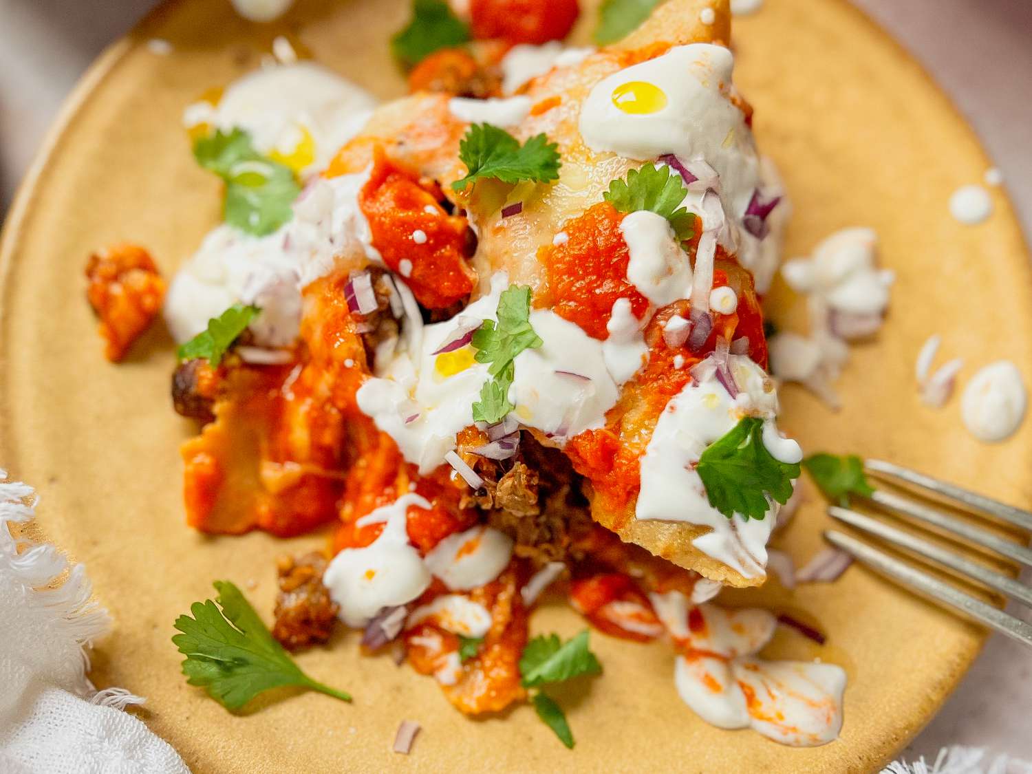Pulled Pork Enchiladas on a Plate Topped with Cilantro, Sour Cream, and Onions