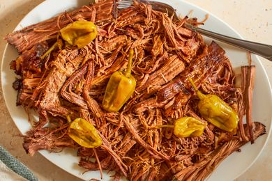 Shredded pot roast on a plate with pepperoncini peppers fork to the side