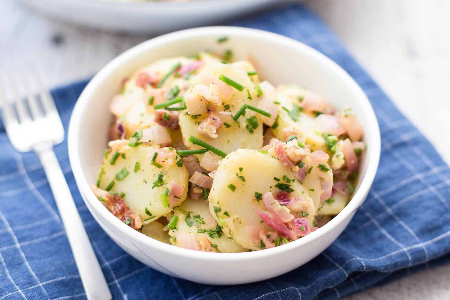 Bowl of German potato salad with chives bacon and diced onions