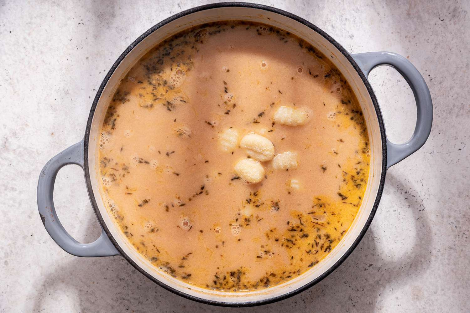 Gnocchi added the soup base in the Dutch oven for creamy vegetable dumpling soup recipe 