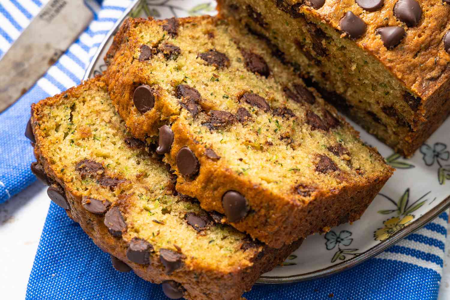 Zucchini bread sliced and on a platter over a table napkin