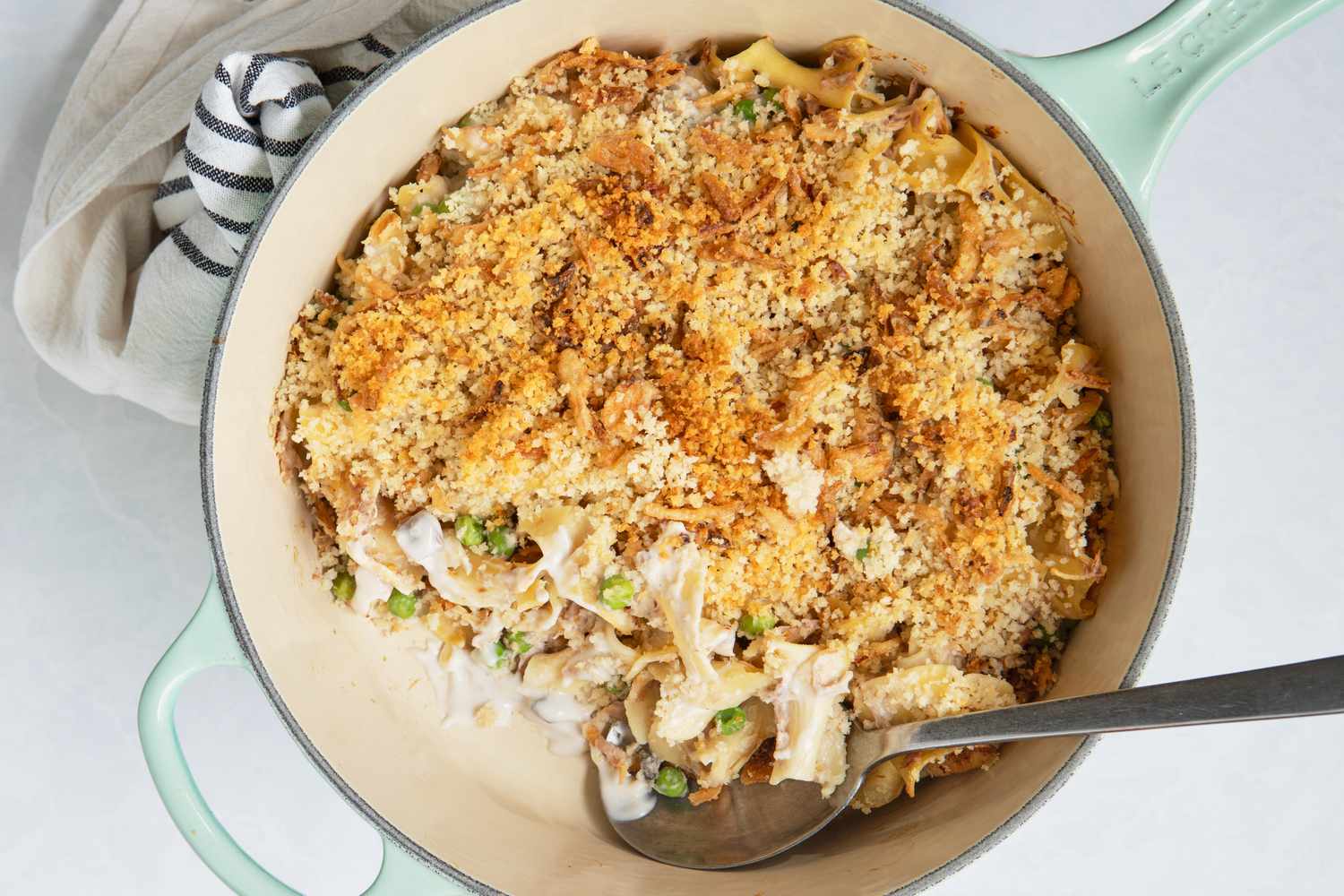 A baked tuna noodle casserole in a dish with a spoon for serving