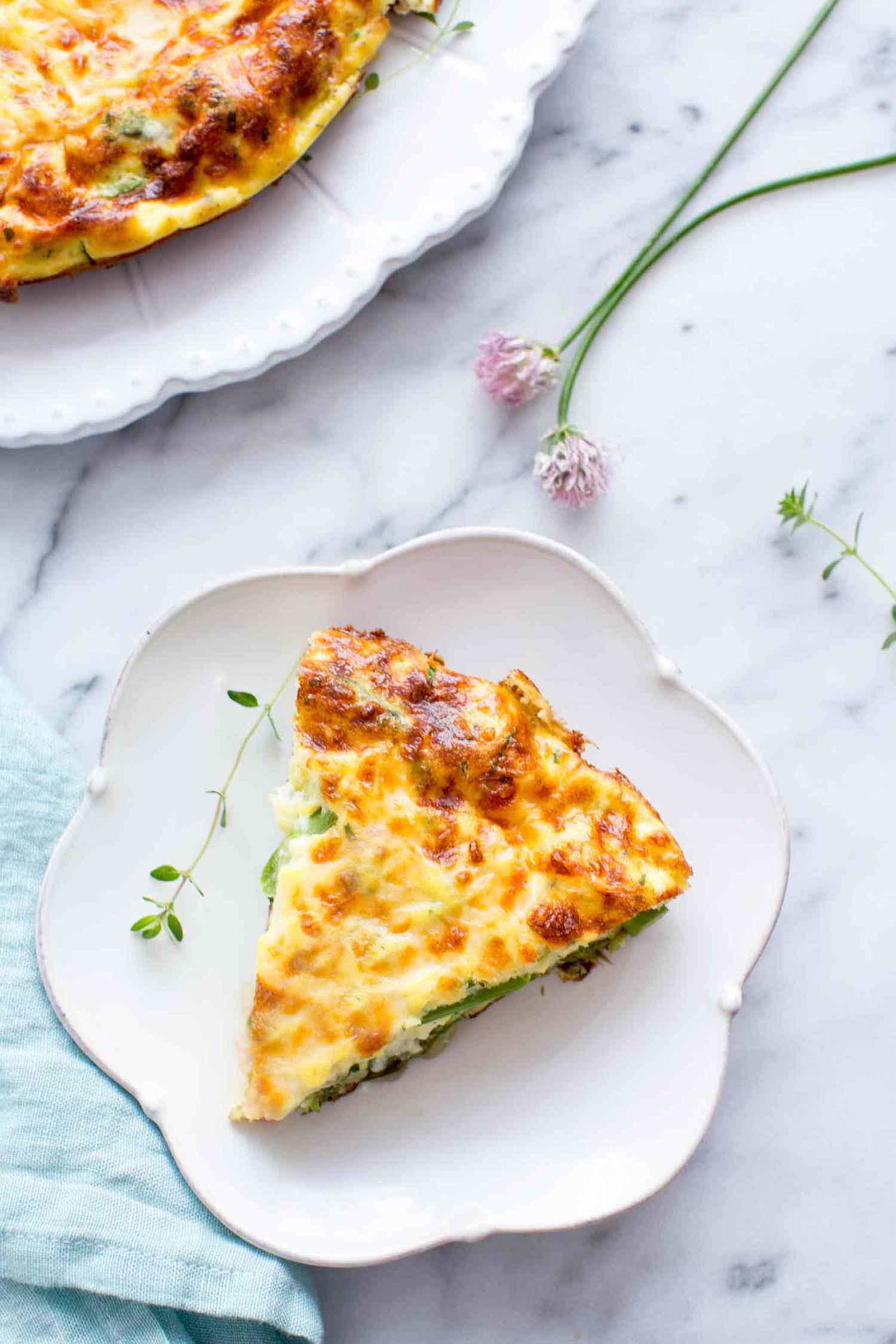Asparagus Frittata slice on a white plate with a sprig of time