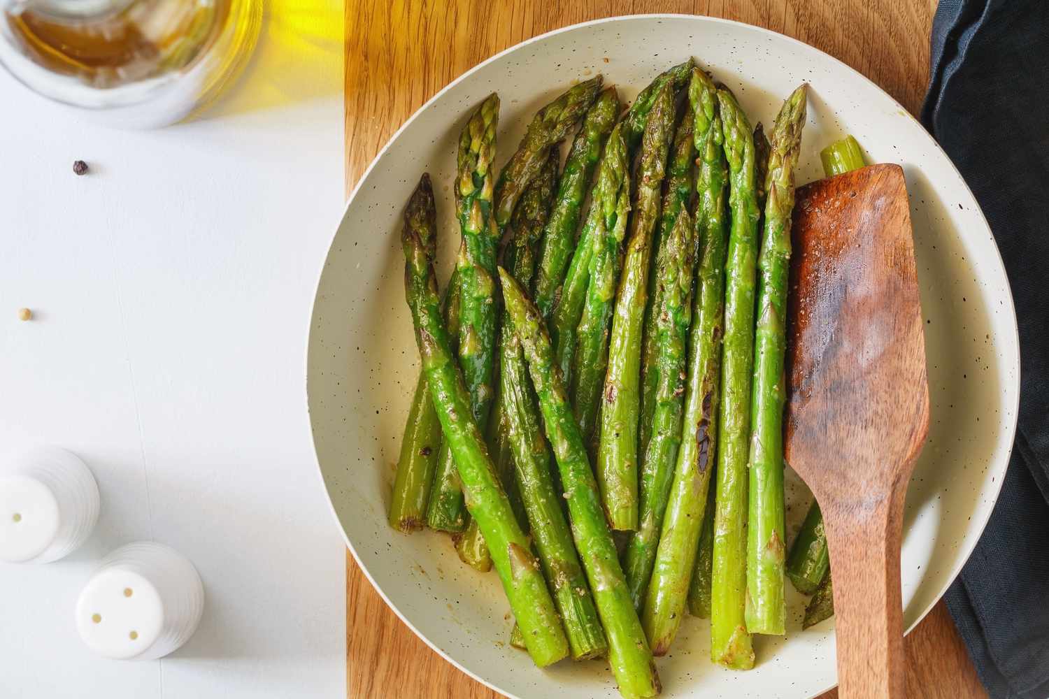 roasted asparagus in a bowl with a wooden spoon on the kitchen counter
