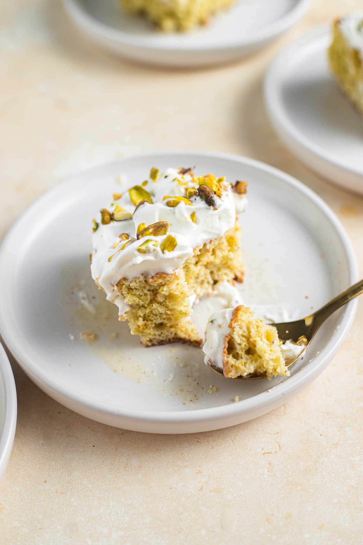 Serving of Pistachio Cardamom Tres Leches Cake on a Plate with Some on a Spoon