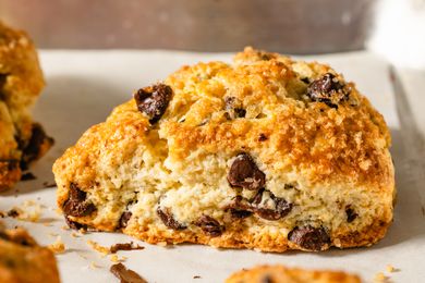 Close-up side view of a golden brown, chocolate chip-studded scone with large sugar crystals on top