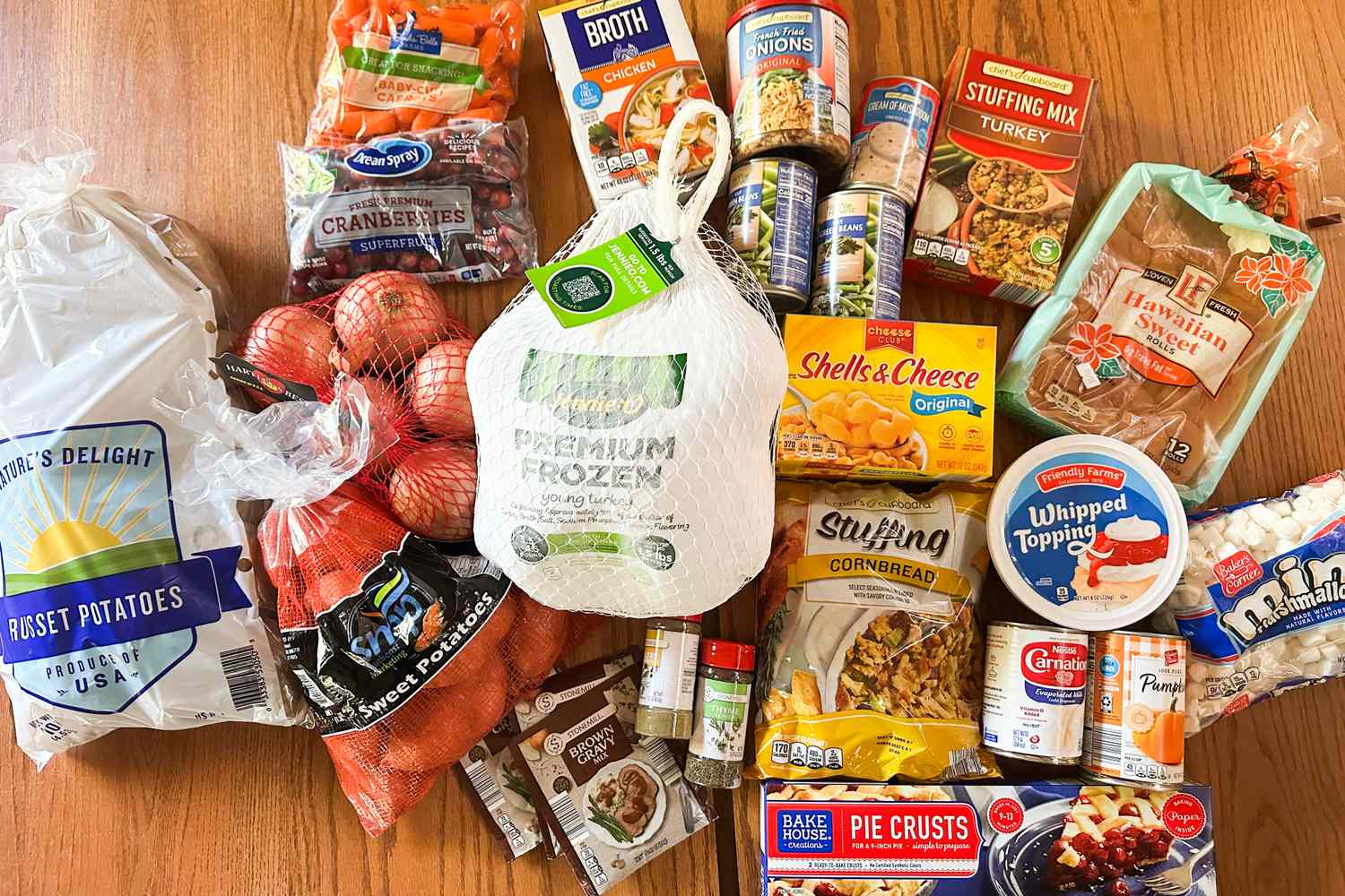 A selection of Thanksgiving food items including a frozen turkey vegetables canned goods and boxed stuffing displayed on a table