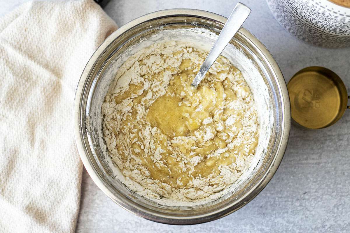 Batter for banana bread with cream cheese being mixed in a metal bowl.