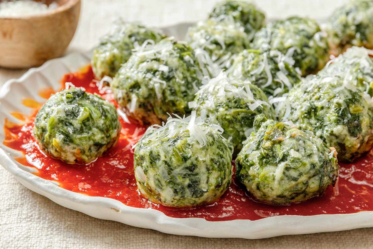 Closeup view of a plate of ravioli gnudi over marinara sauce with a spoon