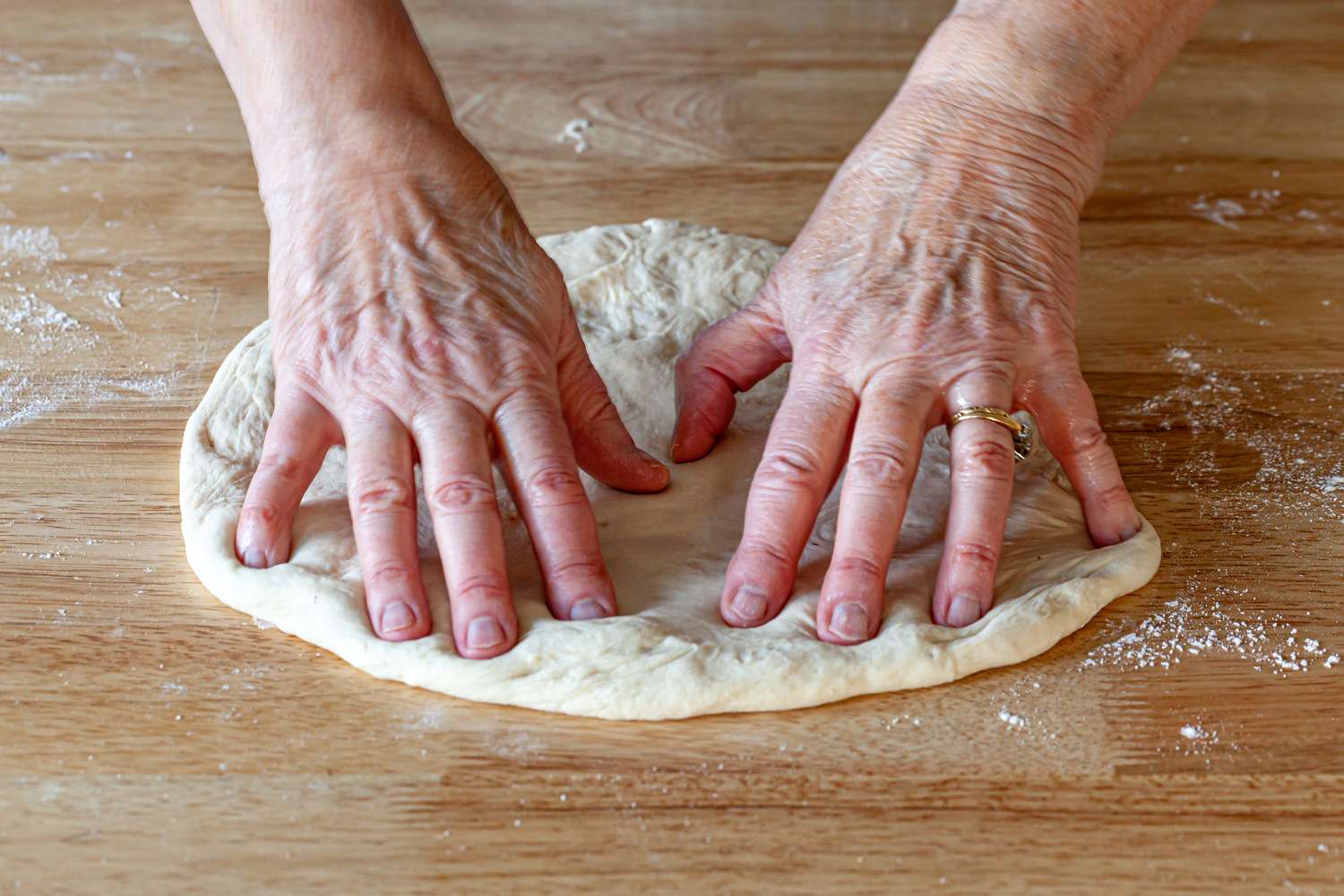 Pressing pizza dough into a circular shape.