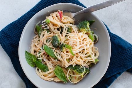 Overhead view of primavera pasta in a bowl with a navy linen underneath.