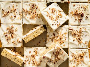 Banana bars with frosting and sprinkled nuts arranged in a grid