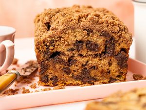 On a Platter, Chocolate Chip Banana Bread Cake Showcasing a Cross Section Cut, a Knife, and a Tea Cup