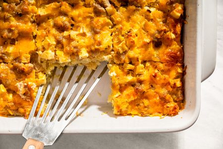 Baked casserole dish with a section removed exposing the interior texture with visible cheese sausage and apple pieces