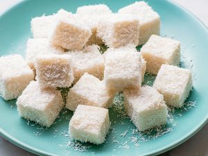 Small cubes of coconut milk pudding served on a plate, topped with shredded coconut