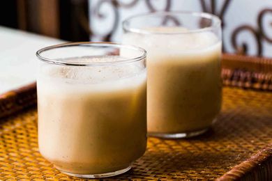 Two glasses of creamy Coquito on a woven mat