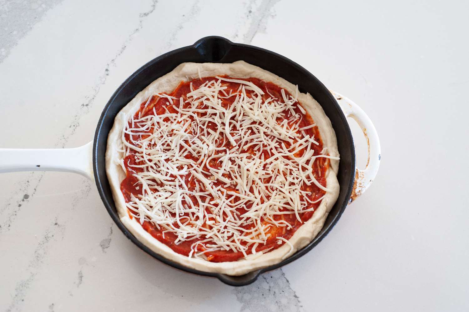 Pizza dough topped with sauce and cheese.