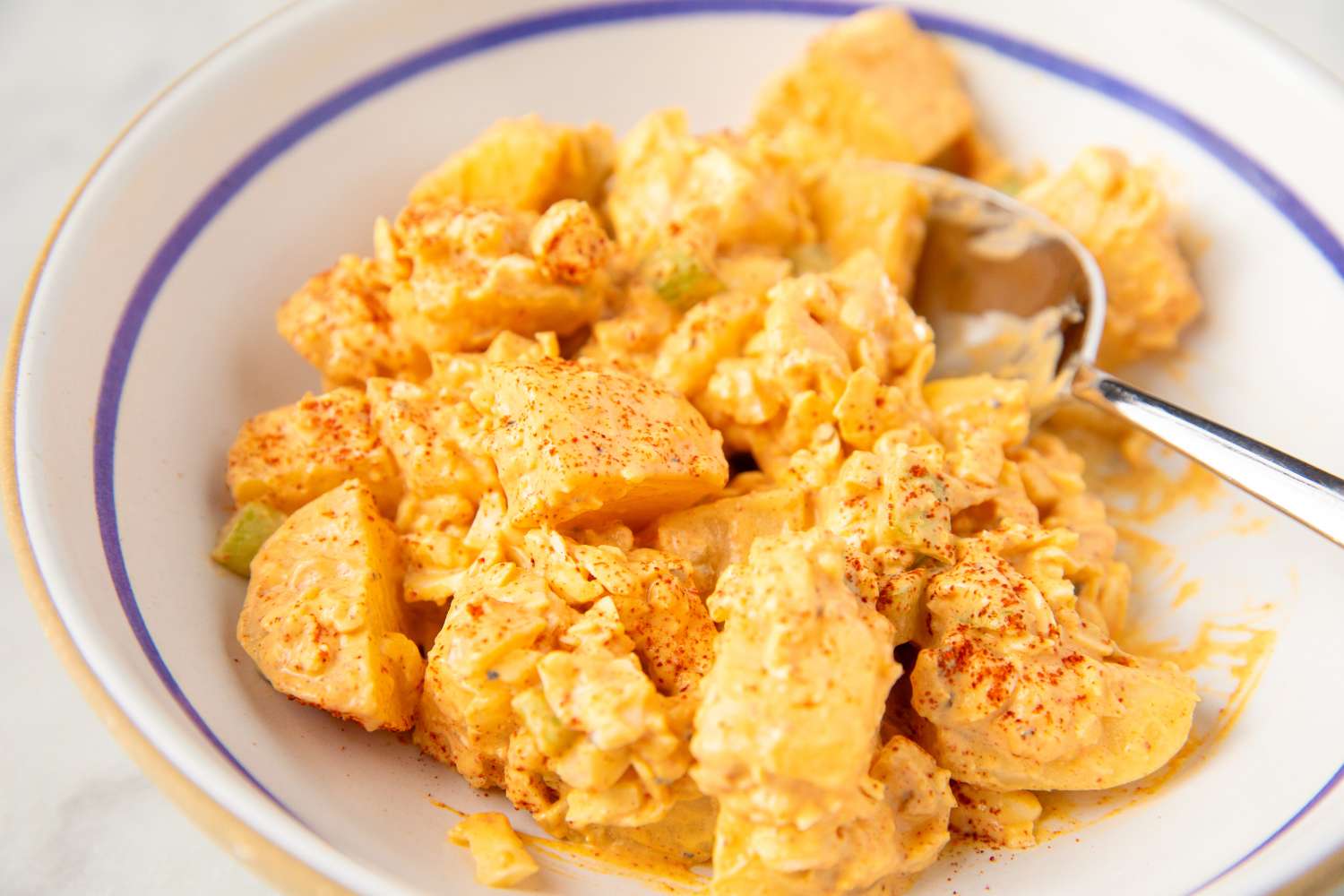 one serving of Deviled Egg Potato Salad in a bowl with a spoon