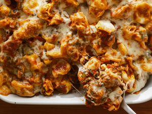 Casserole dish of tortellini casserole, serving spoon removing a cheesy spoonful