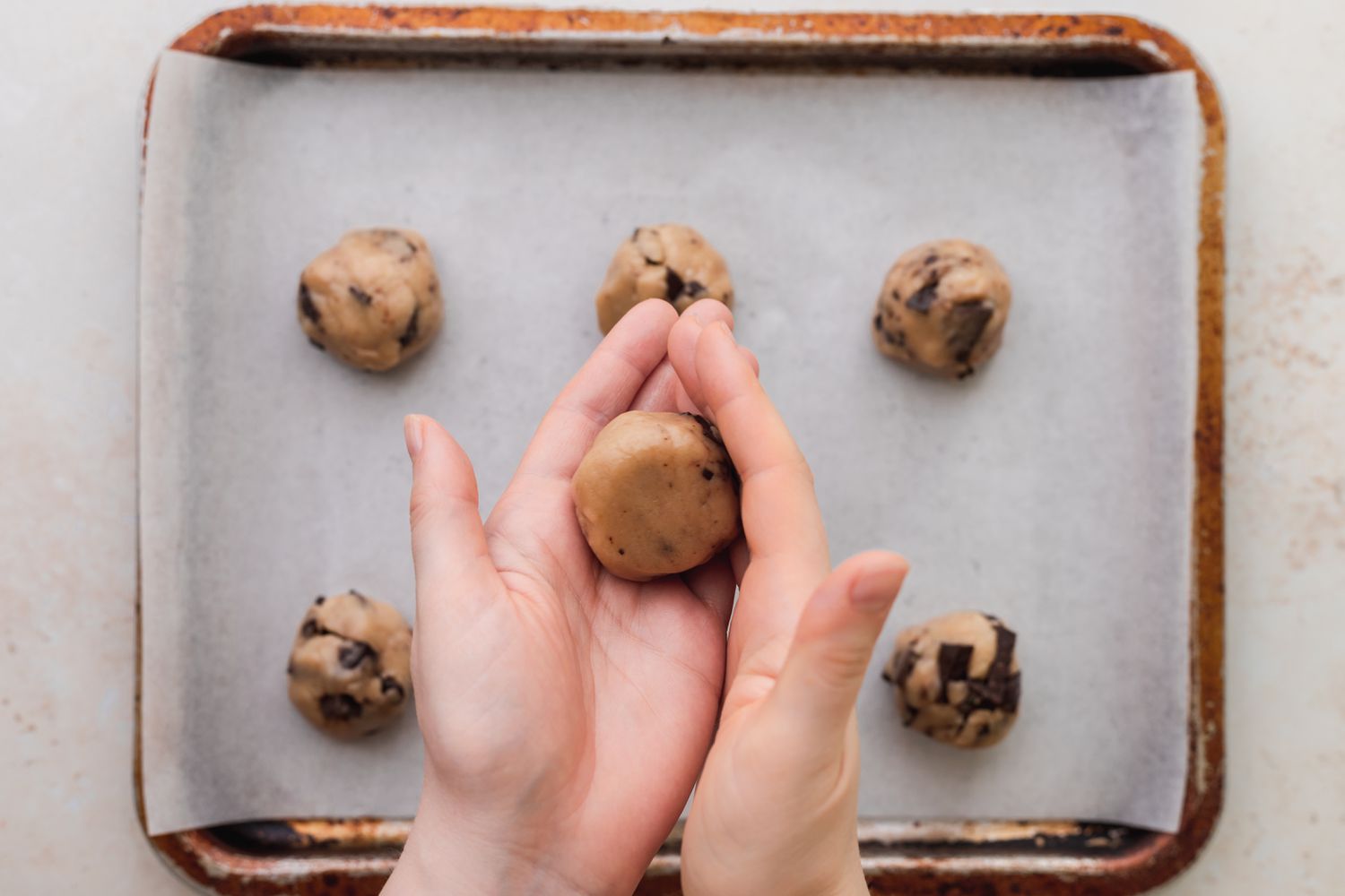 Rolling dough into balls and putting on a parchment covered baking sheet
