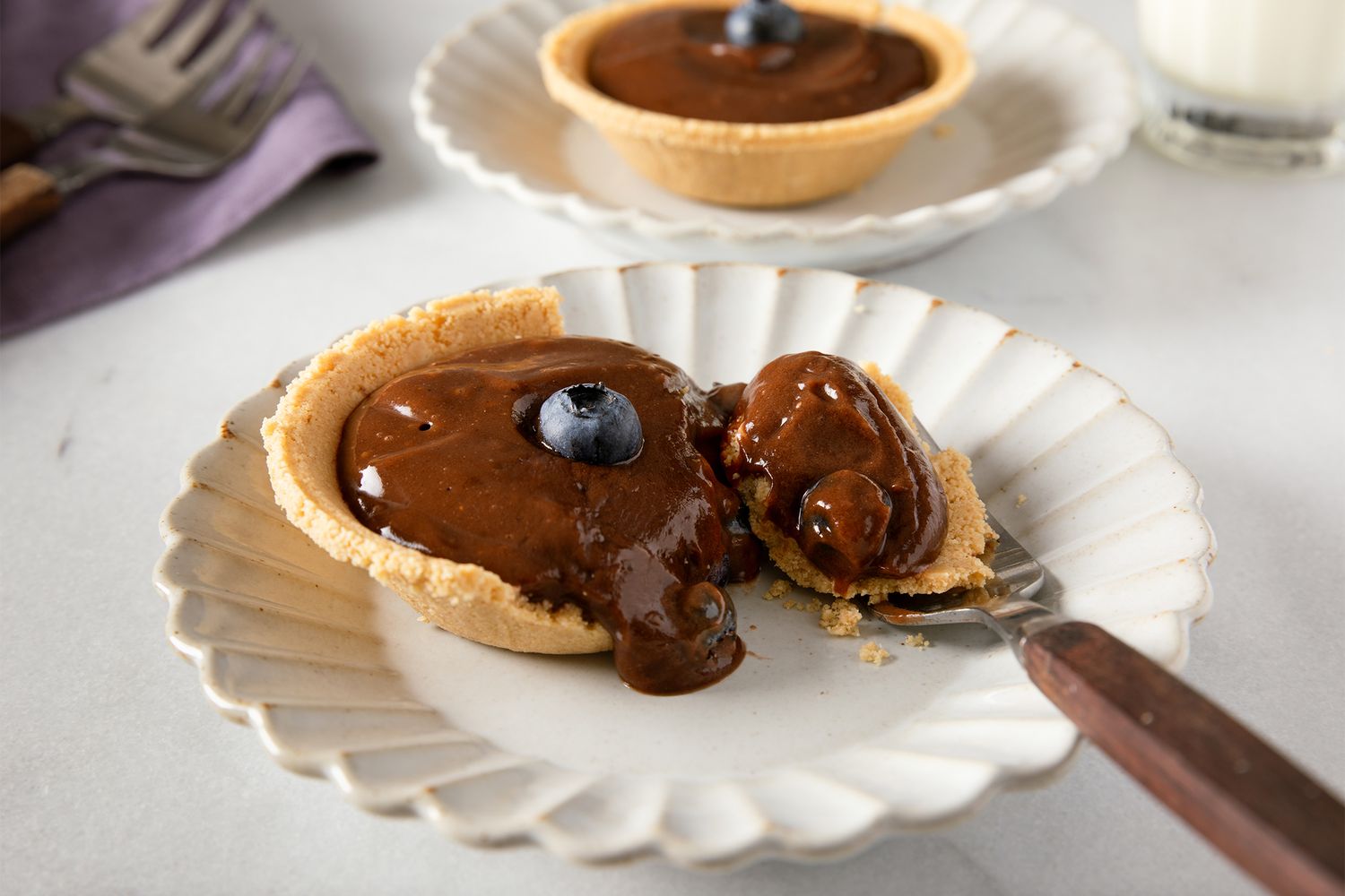 Mini chocolate pudding pie on a plate with a spoon garnished with a blueberry