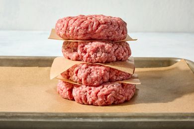 Stack of uncooked hamburger patties on parchment paper