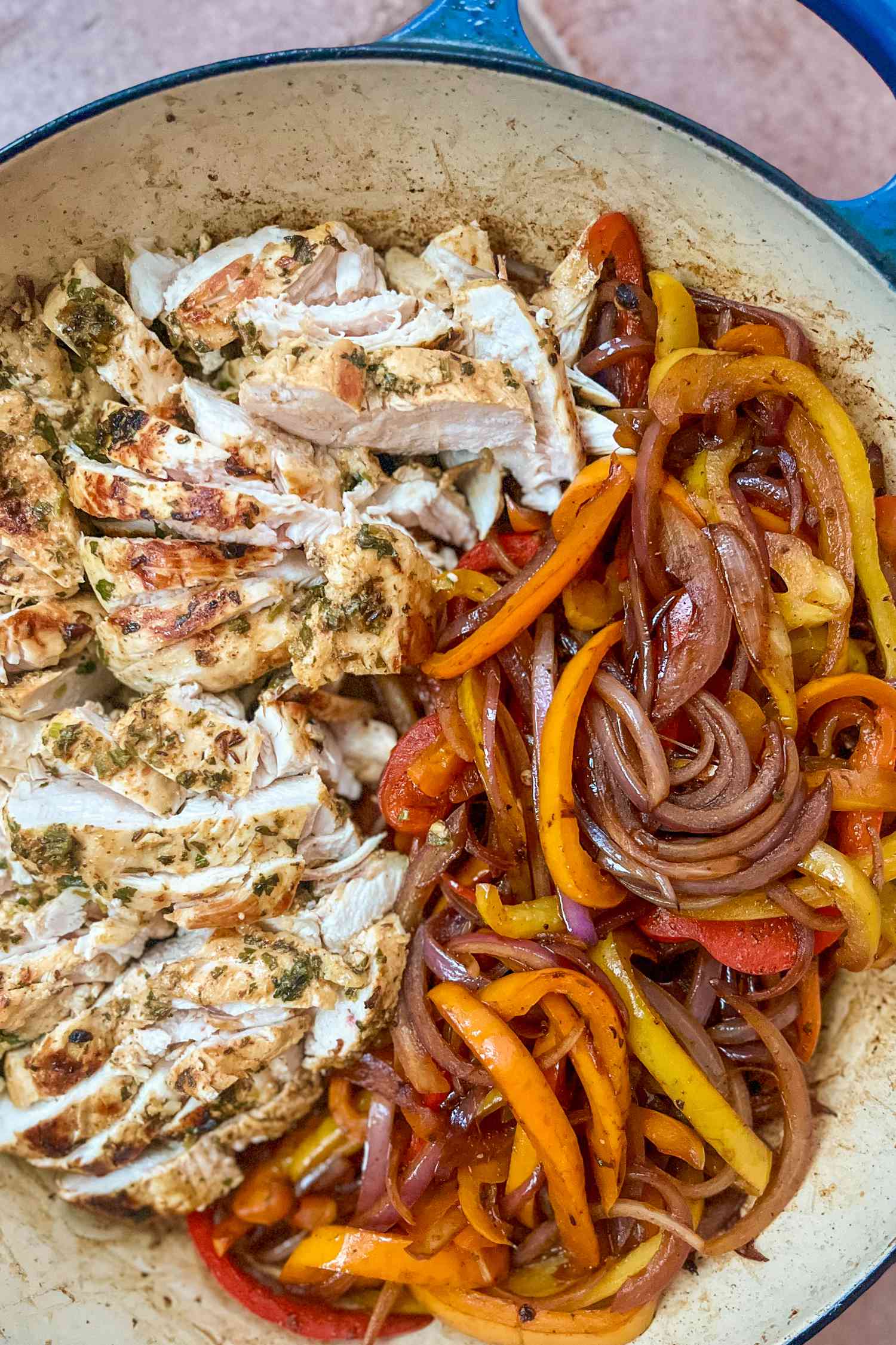 chicken in a skillet with sauteed onions and bell peppers