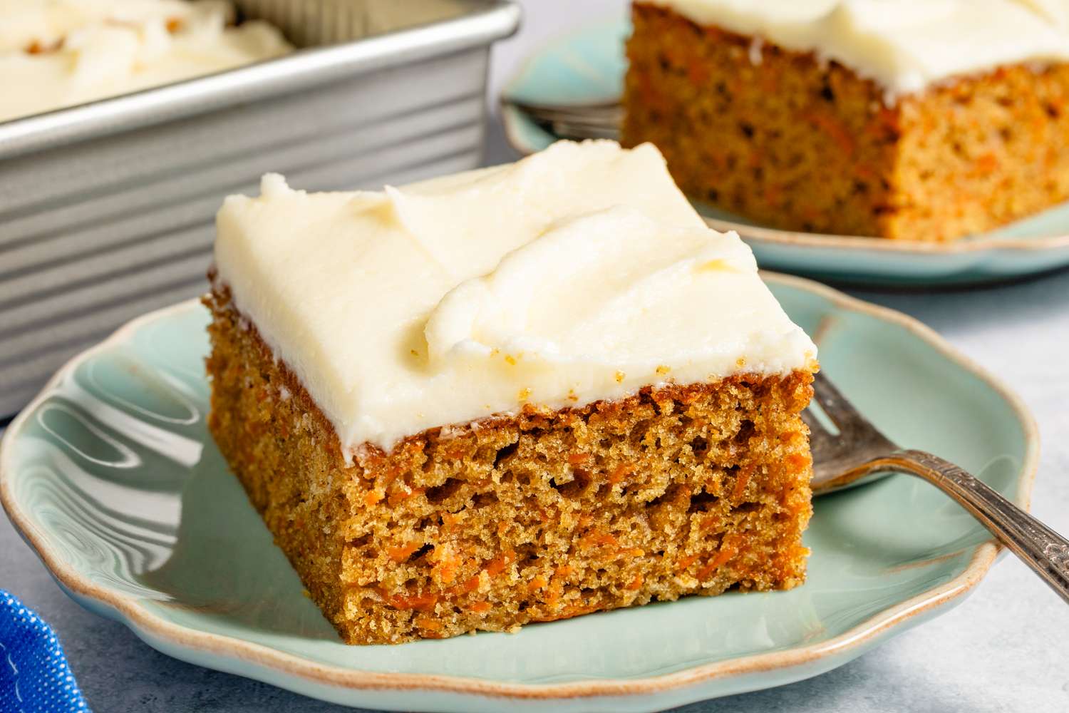 A slice of frosted carrot cake on a plate