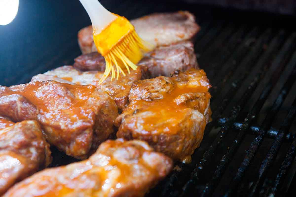 brushing sauce over country ribs cooked low and slow