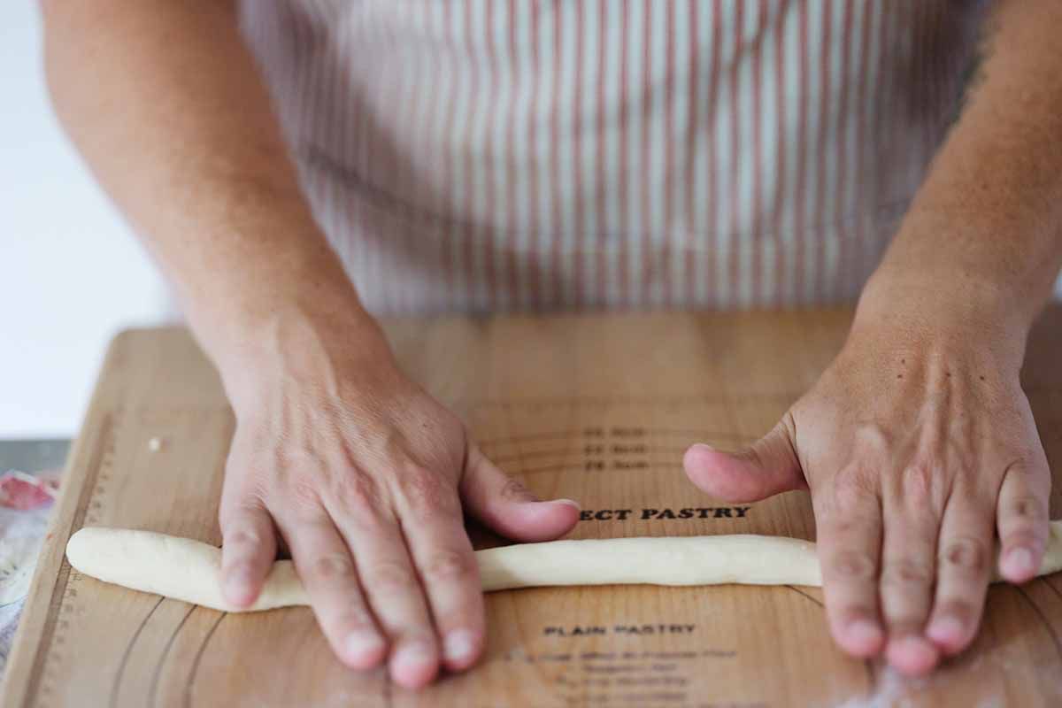 Rolling each ball of dough into a long ropes