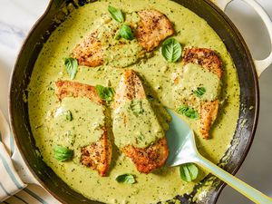 Chicken breasts cooked in pesto sauce and garnished with basil in a skillet