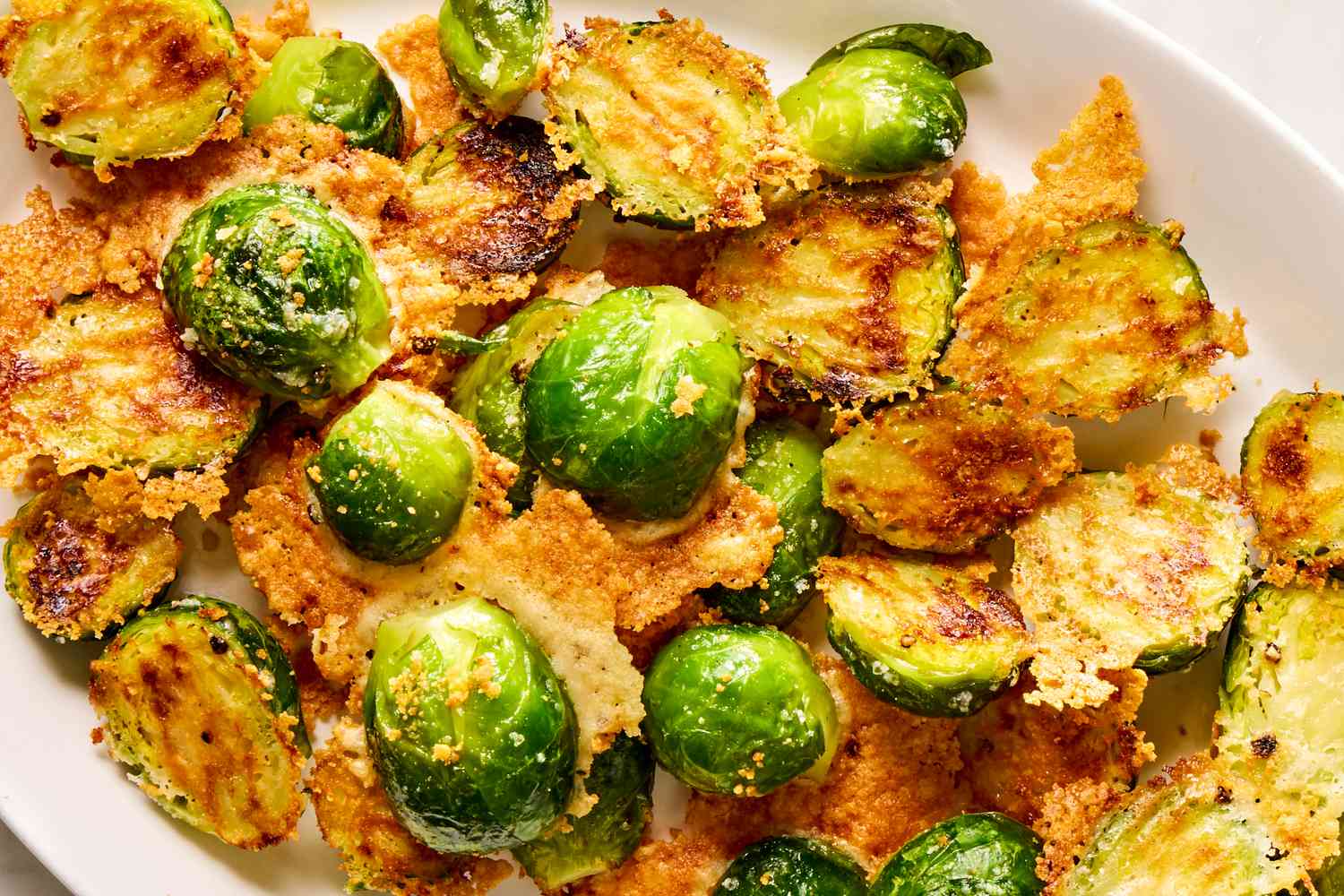 Closeup view of a white plate of roasted brussels sprouts and parmesan