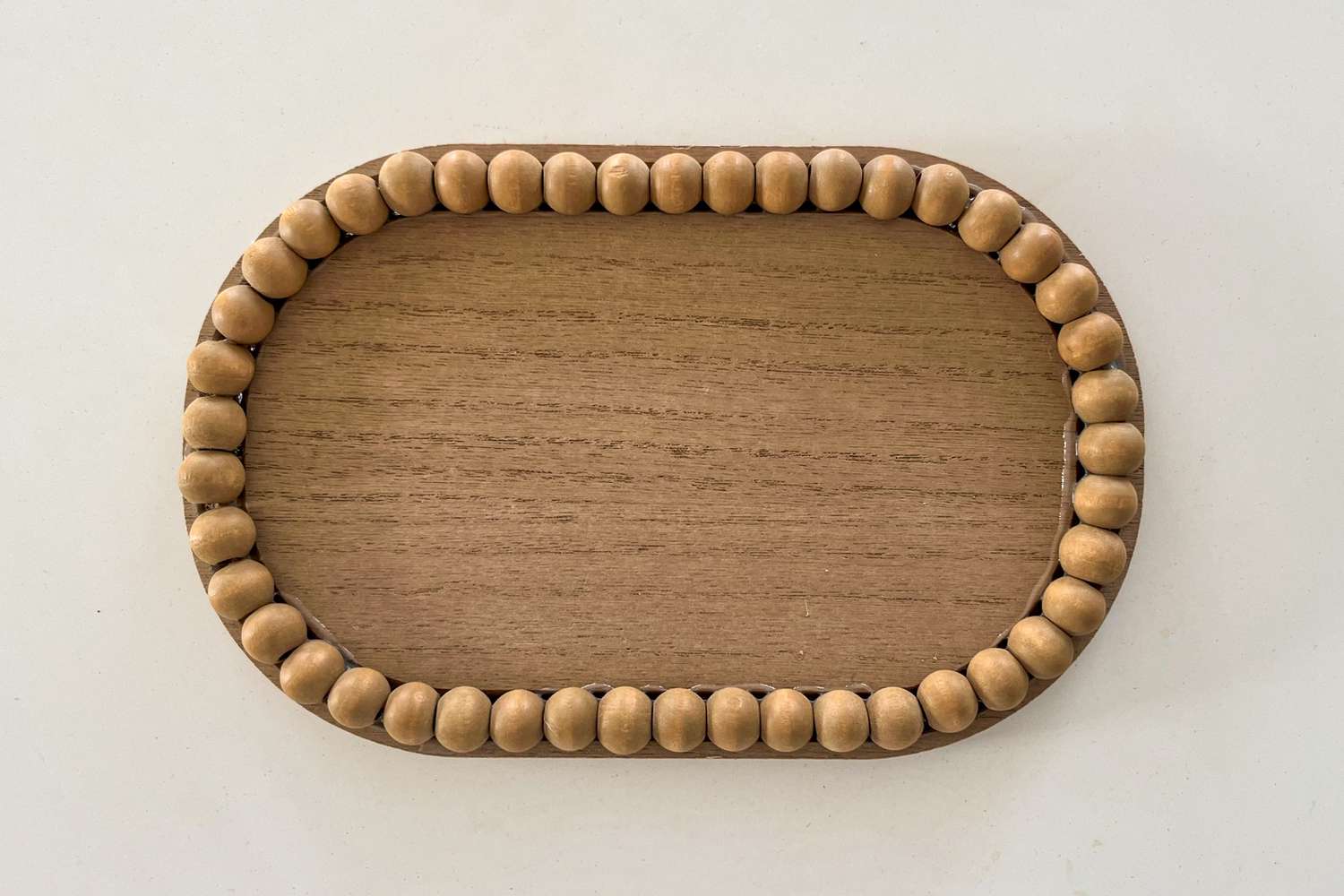 Overhead view of a farmhouse-inspired wooden tray from Dollar Tree on an off-white background