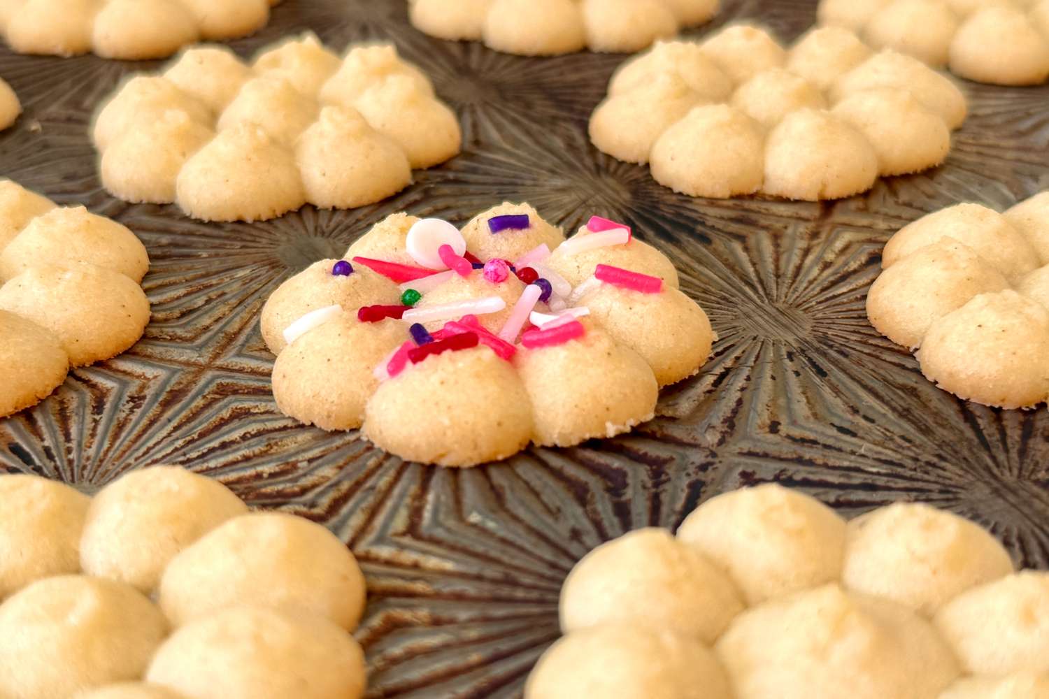 Spritz cookies arranged on a decorative tray one cookie topped with colorful sprinkles