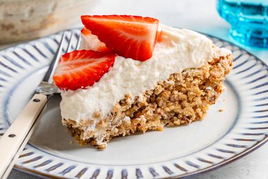 soda cracker pie slice (topped with whipped cream and fresh strawberries) on a small plate with a fork